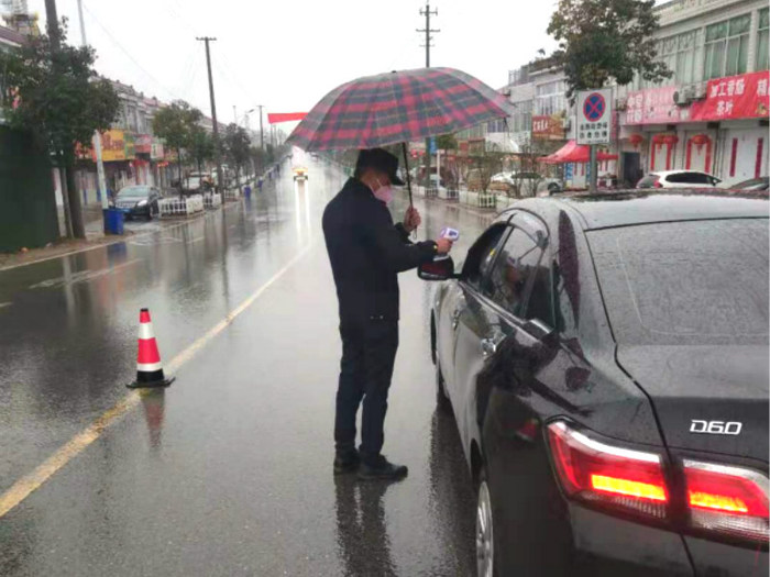 袁宏超队长在大雨中执勤图片,为过往车辆中的人员测量体温_meitu_1.jpg